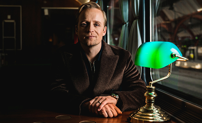 Andreas Weise sitter i en tågkupé med en grön läslampa på borden