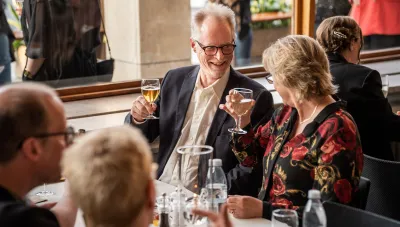 Kvinna och man skålar vid ett bord i foajén