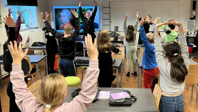 Barn i et klassrum sträcket upp händerna under en operalektion