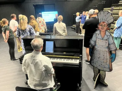 En grupp människor samlas runt ett piano